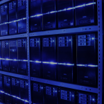 Sistemas computacionais em uma sala de um centro de dados, também conhecido por data center. Ambiente iluminado por luz em tom azul.