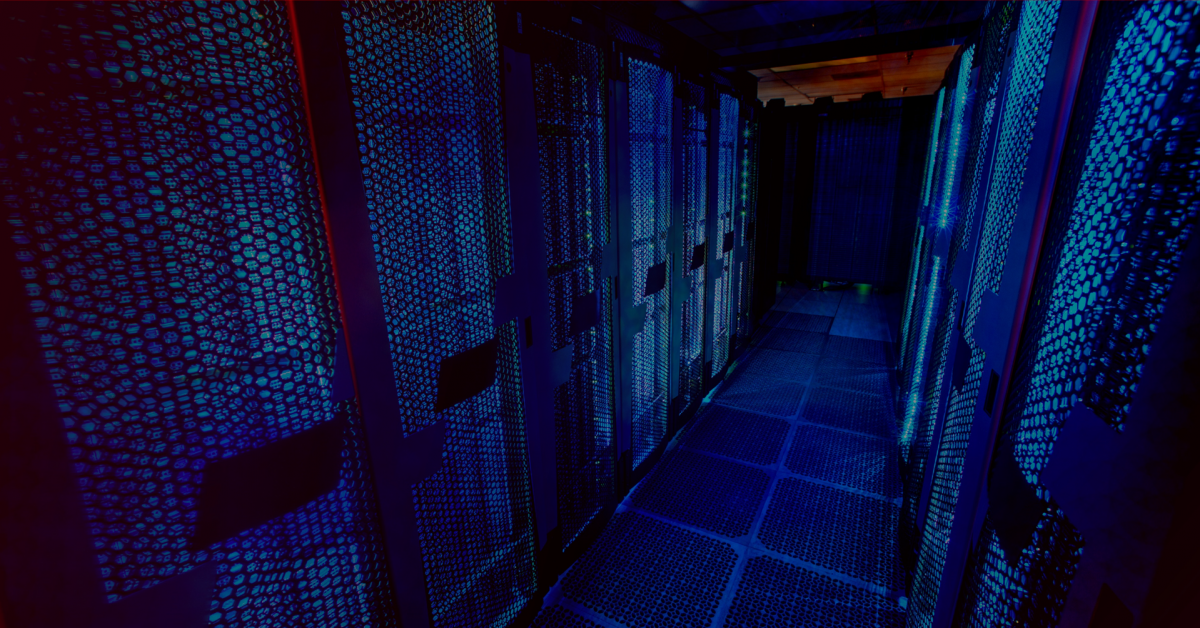 Sala de um centro de dados, também conhecido por data center. Ambiente iluminado por luz em tom azul.
