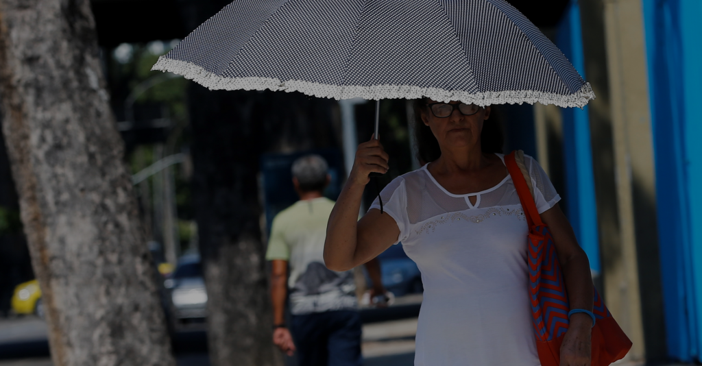 Senhora segurando guarda-chuva em dia quente para se proteger do sol na rua