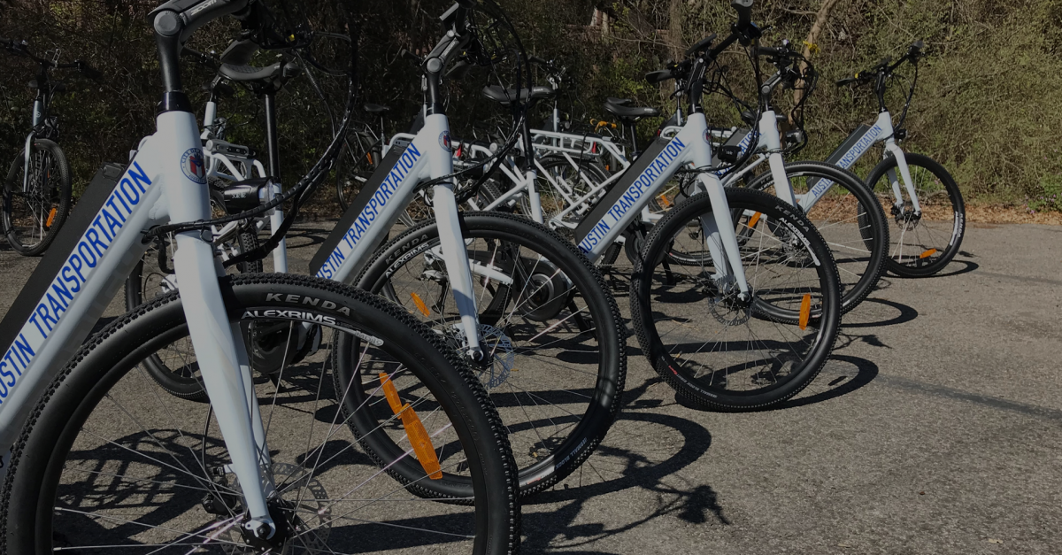 Imagem mostra várias bicicletas elétricas posicionadas uma ao lado da outra em um espaço ao ar livre.