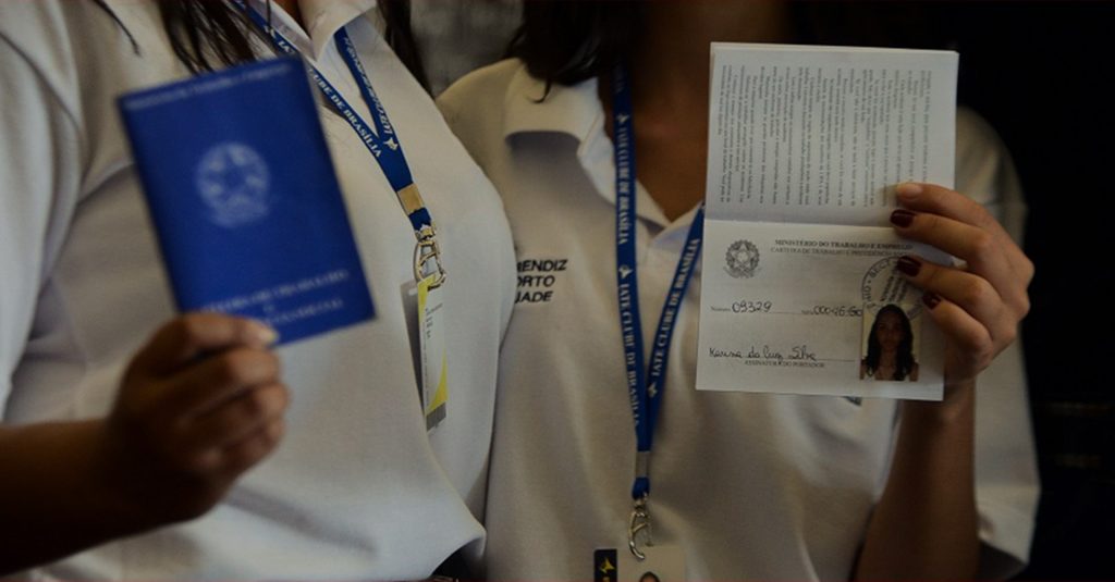 Jovens exibem carteira de trabalho com registro de primeira experiência profissional como aprendizes