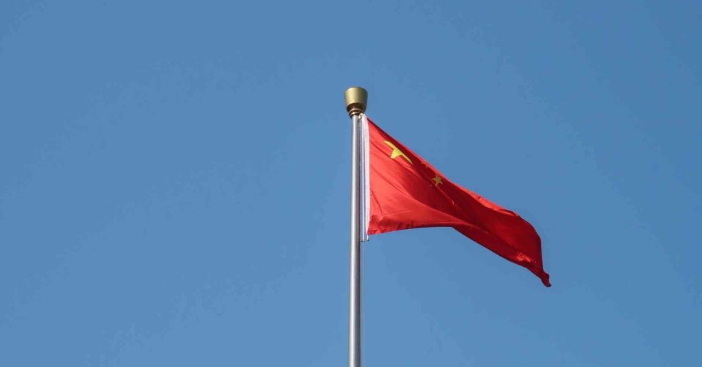 China e a transição energética. Bandeira da China em céu azul