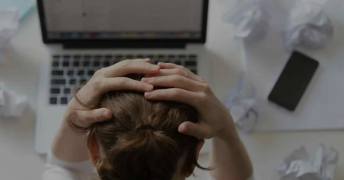 Pessoa coloca as mãos na cabeça enquanto olha para a tela do notebook