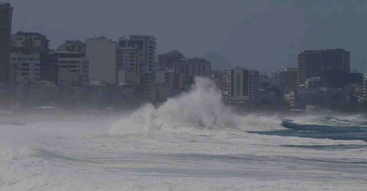 Imagem de praia em cenário urbano, com ondas fortes