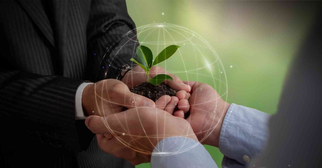 Mãos de executivos reunidas no centro da imagem, segurando uma muda de planta em uma sobreposição com um globo